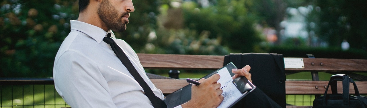 man in a suit writing in a notebook