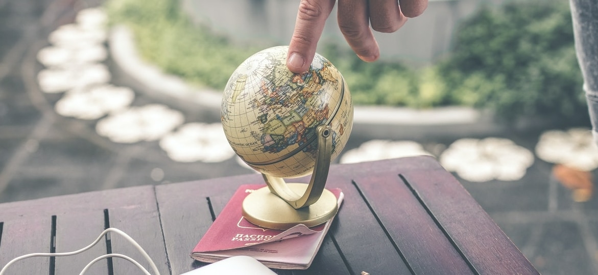 person touching an earth globe sitting on a passport