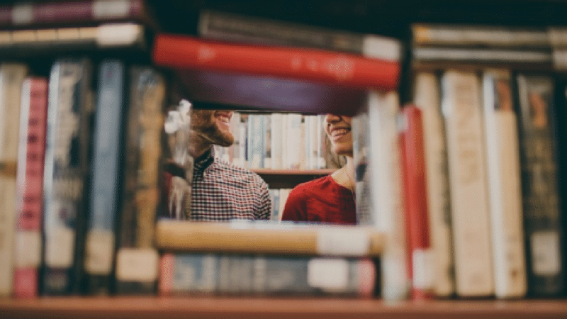 deux personnes parlent dans une bibliothèque