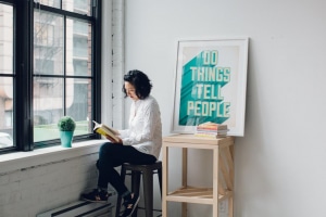 femme aissse sur un tabouret lit un livre