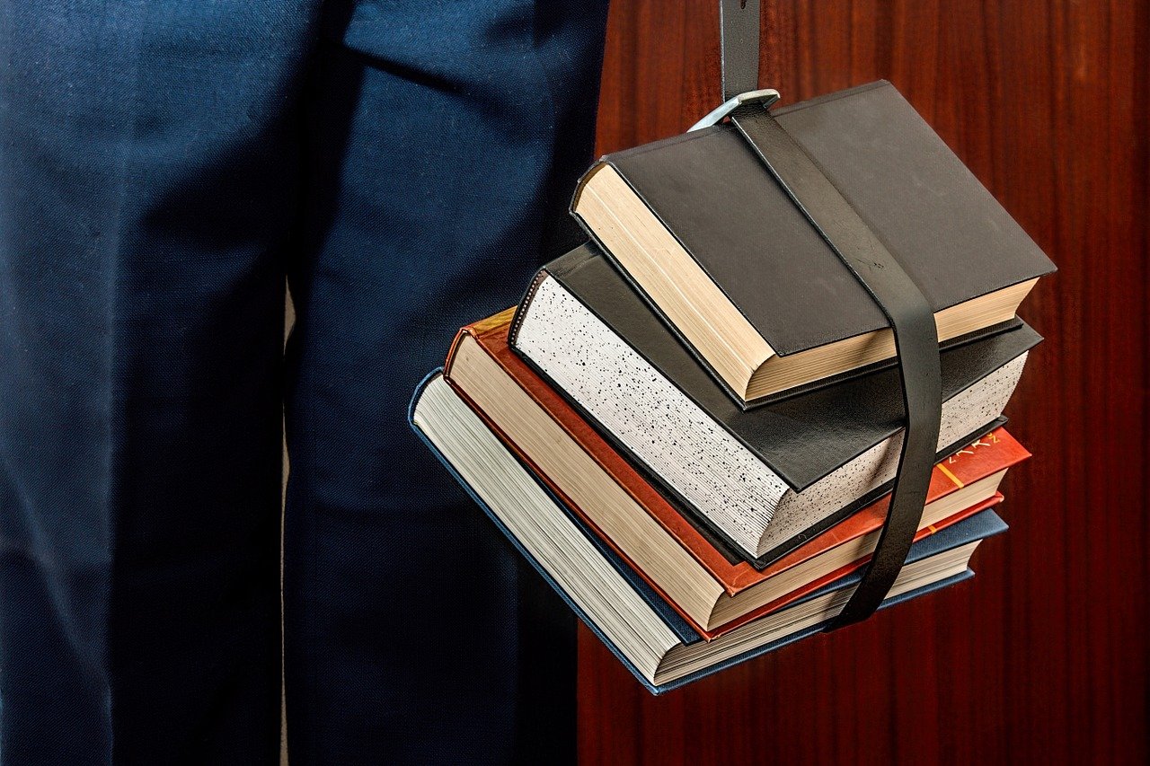 man holding multiple books