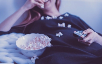 woman eating popcorn and watching tv