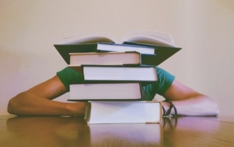 person hiding behind a pile of books