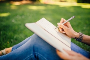 girl-writing-on-her-knee-in-a-park