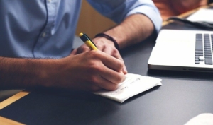 man-writing-on-a-piece-of-paper