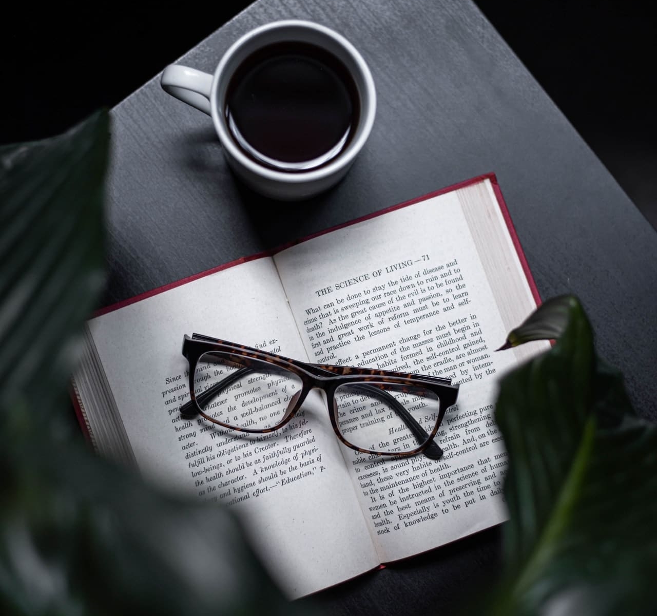 a book with glasses on it and a cup of coffee next to it