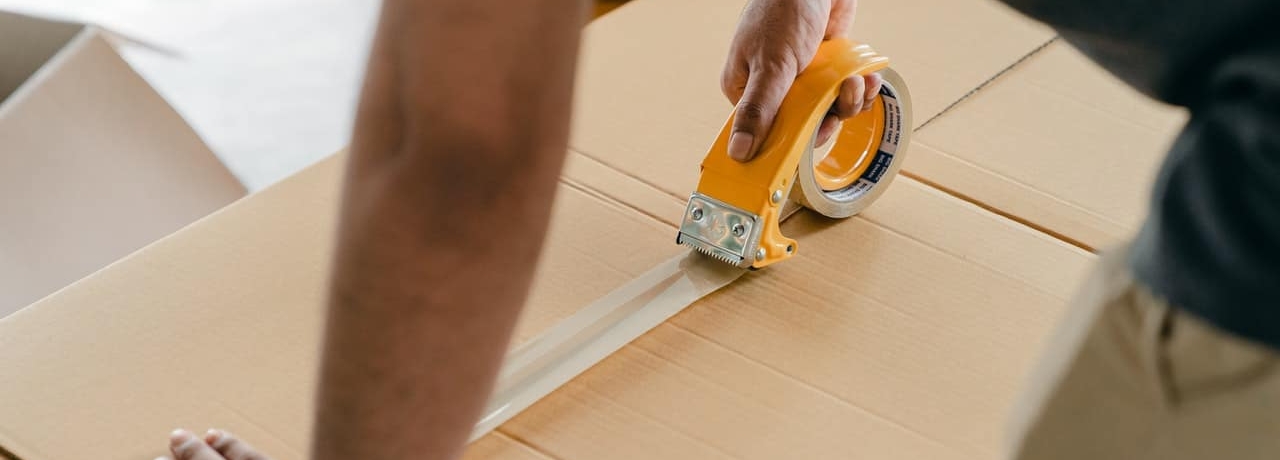 man closing a box with tape