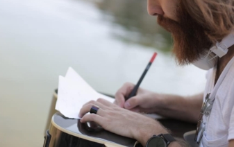 bearded man writing in a notebook