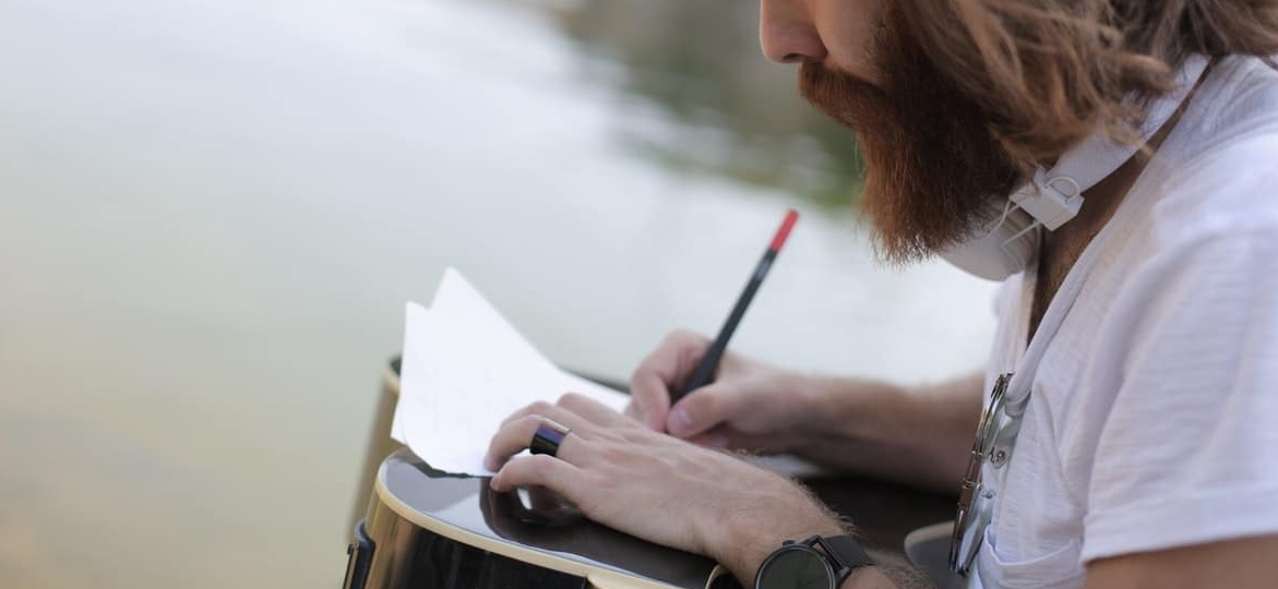 bearded man writing in a notebook