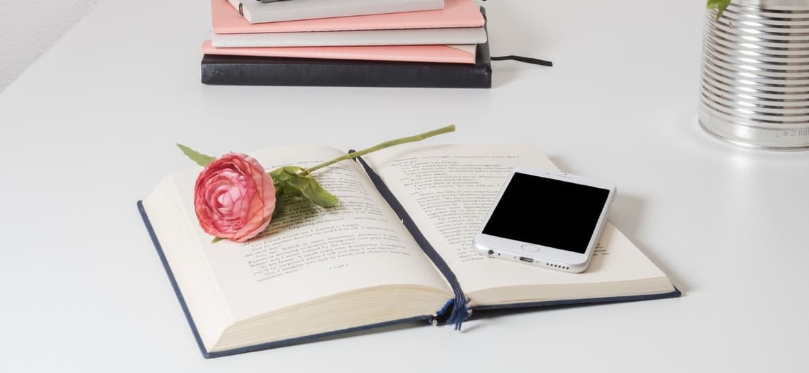 une fleur et un telephone sur un livre ouvert